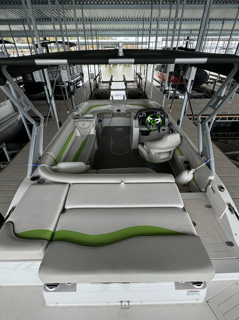 Slide: The Image of 2018 Starcraft Starstep 221 boat with green accents, docked under a covered marina. - 6