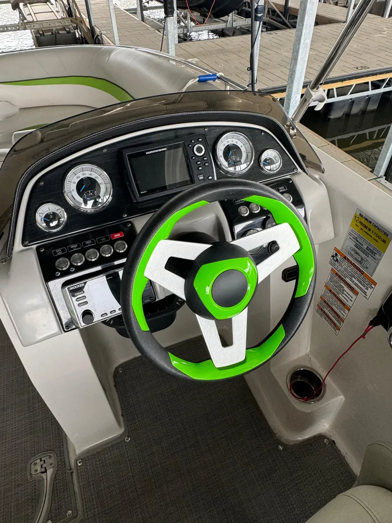 Slide: The Image of 2018 Starcraft Starstep 221 boat dashboard with green-accented steering wheel and control panel. - 7