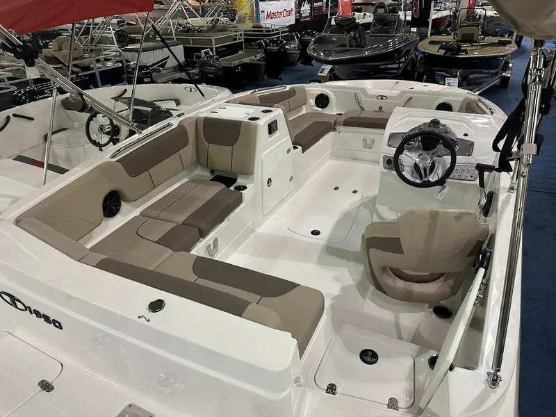 Slide: The Image of 2025 Tahoe 1950 boat interior with beige seating and steering wheel, displayed at a boat show. - 3