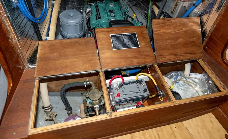 Slide: The Image of Engine compartment of a 1977 Baltic 42 sailboat, featuring battery and mechanical components. - 24