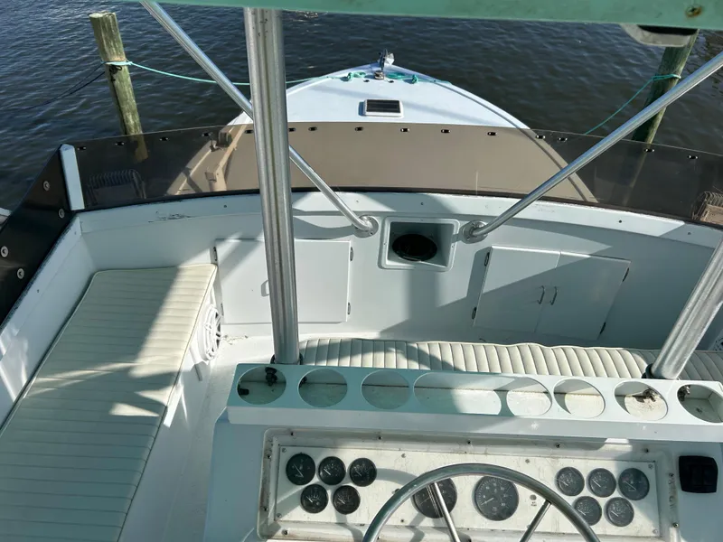 Slide: The Image of 1989 Post 43 boat cockpit with steering wheel, gauges, and seating, docked by the water. - 10