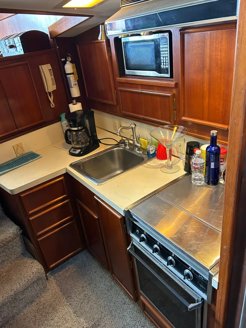Slide: The Image of 1989 Post 43 yacht kitchen with microwave, stove, sink, and wooden cabinets. - 23