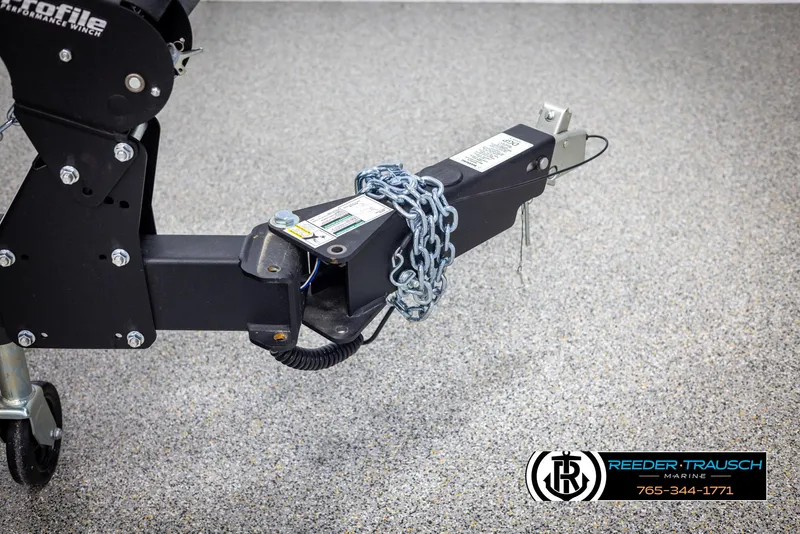 Slide: The Image of Trailer hitch of 2025 Lund 1875 Pro V Bass XS, secured with chain, on speckled floor. - 47