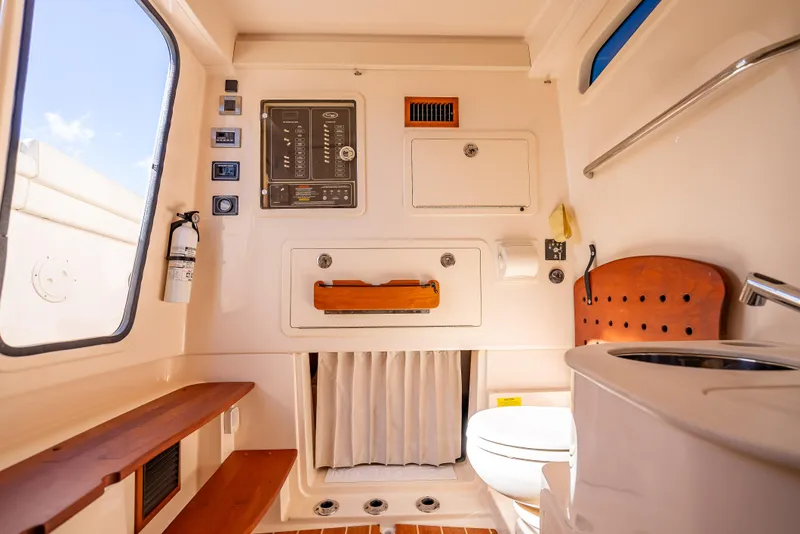 Slide: The Image of Interior of 2023 Grady-White 336 Canyon boat, featuring control panel and compact bathroom amenities. - 18