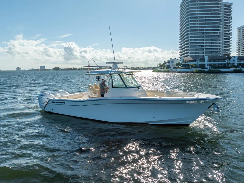 Slide: The Image of 2023 Grady-White 336 Canyon boat cruising near waterfront buildings. - 2