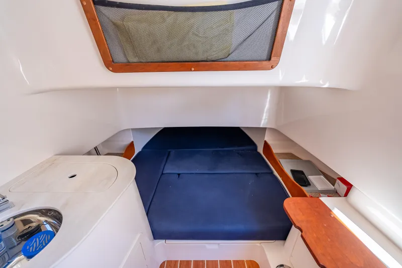 Slide: The Image of 2023 Grady-White 336 Canyon cabin interior with blue cushions and wooden accents. - 21