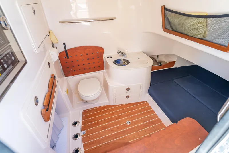 Slide: The Image of 2023 Grady-White 336 Canyon boat interior with toilet, sink, and wooden flooring. - 23