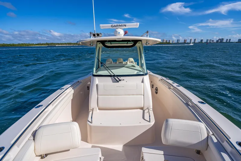 Slide: The Image of 2023 Grady-White 336 Canyon boat on open water, clear sky, city skyline in background. - 28