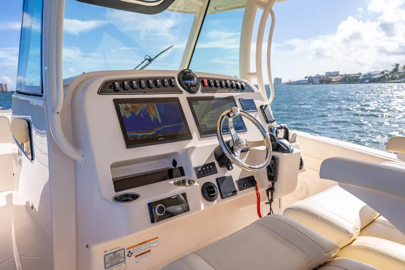 Slide: The Image of 2023 Grady-White 336 Canyon boat dashboard with steering wheel and navigation screens. - 37