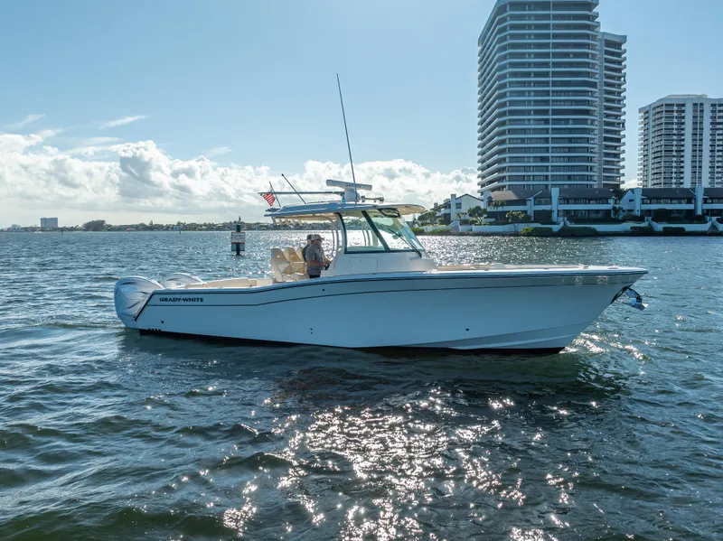 Slide: The Image of 2023 Grady-White 336 Canyon boat on water near modern buildings. - 5