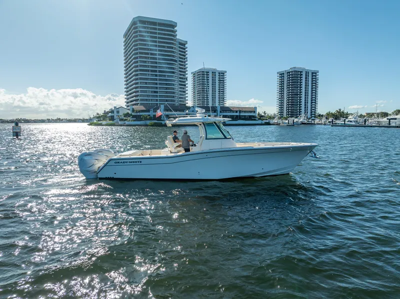 Slide: The Image of 2023 Grady-White 336 Canyon boat cruising near waterfront skyscrapers. - 6
