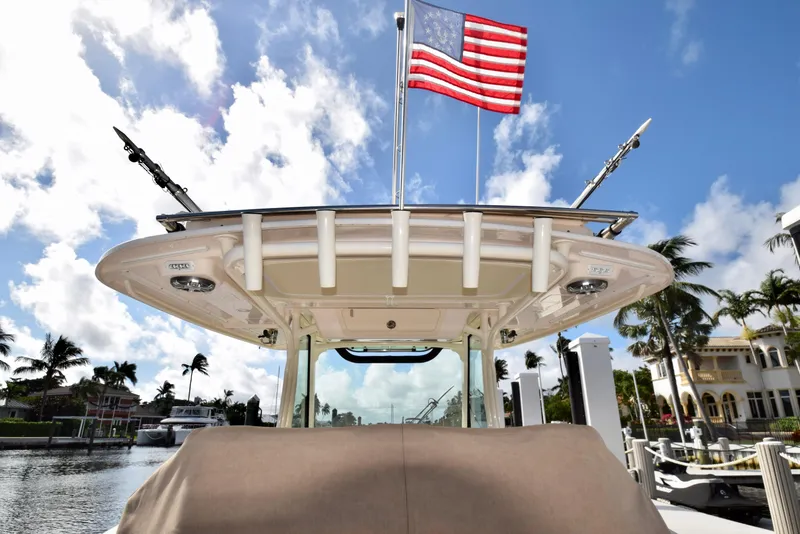 Slide: The Image of 2023 Grady-White 336 Canyon boat with American flag, docked under blue sky. - 64