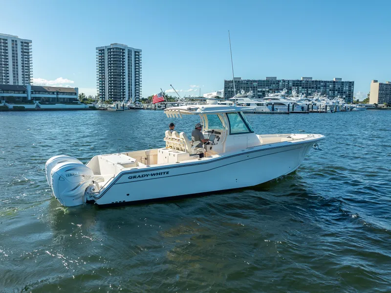 Slide: The Image of 2023 Grady-White 336 Canyon boat cruising near waterfront buildings. - 7