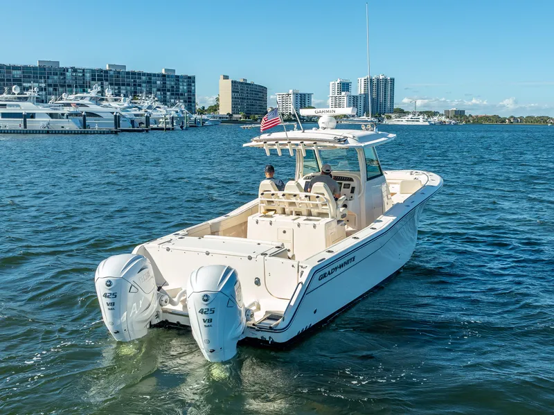 Slide: The Image of 2023 Grady-White 336 Canyon boat cruising in a marina with city skyline. - 9