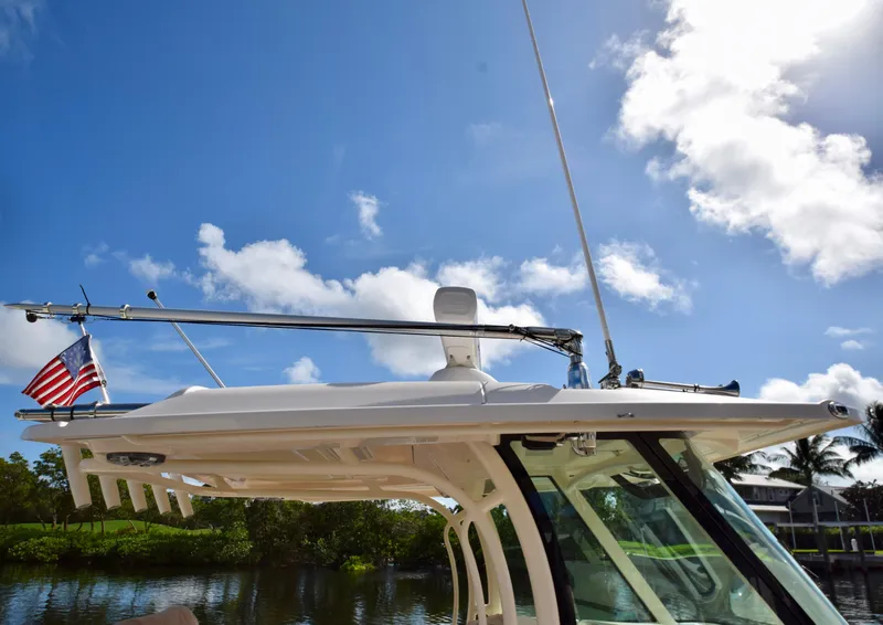 Slide: The Image of 2023 Grady-White 336 Canyon boat with American flag under clear blue sky. - 98