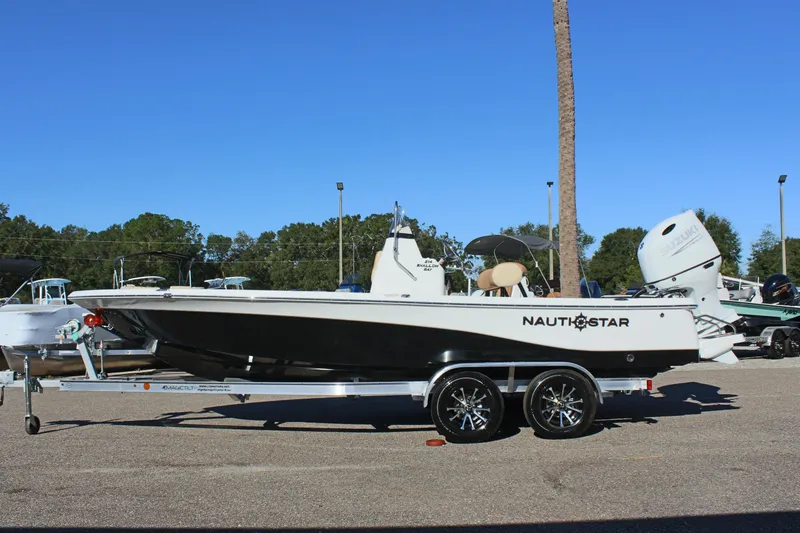Slide: The Image of 2025 NauticStar 214 Shallow Bay boat on trailer, side view, outdoors. - 2