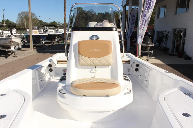Slide: The Image of 2025 NauticStar 214 Shallow Bay boat interior with tan seating, displayed outdoors. - 27