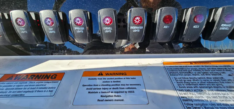 Slide: The Image of Control panel of 2023 Yamaha Boats 255 FSH Sport E with warning labels and switches. - 31