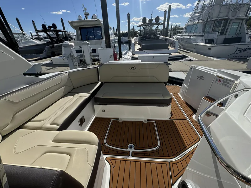 Slide: The Image of 2018 Monterey 335 SY boat interior with cushioned seating and wooden deck at marina. - 7