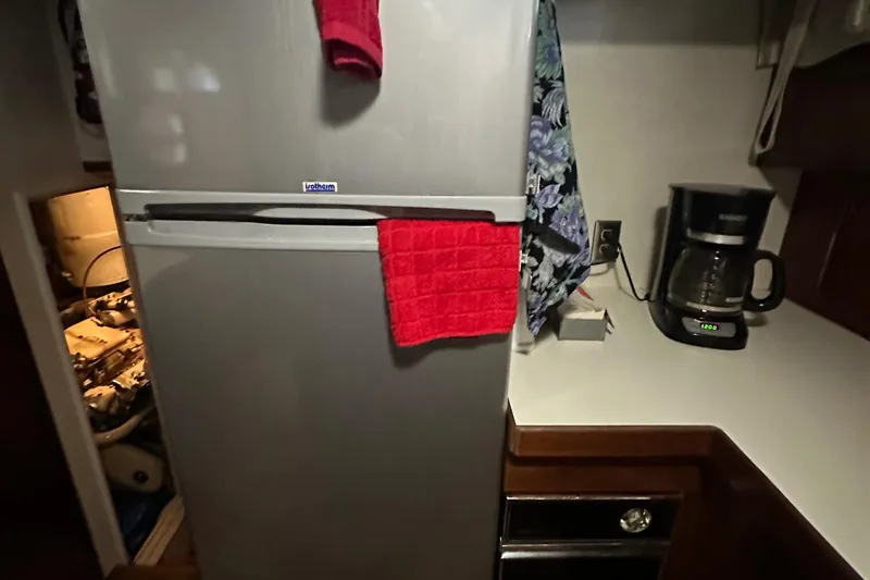 Slide: The Image of 1974 Hatteras 58 Yachtfish kitchen with fridge, coffee maker, and red towel. - 27