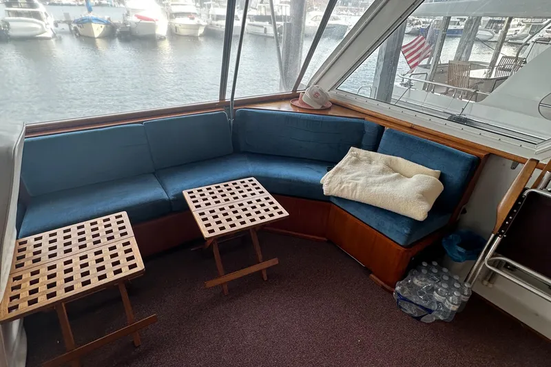 Slide: The Image of 1974 Hatteras 58 Yachtfish interior with blue seating, wooden tables, and marina view. - 3