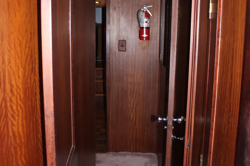 Slide: The Image of Wood-paneled hallway inside 1974 Hatteras 58 Yachtfish, featuring a fire extinguisher. - 34