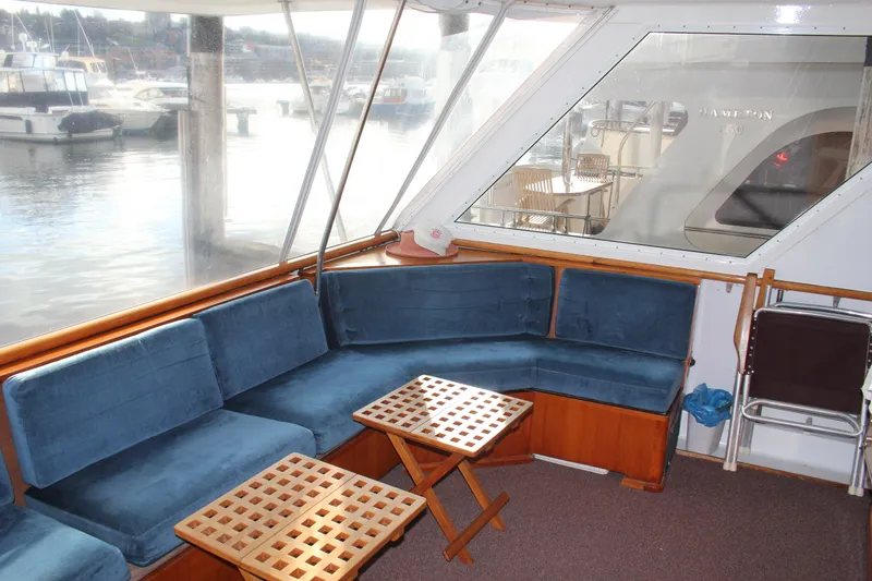 Slide: The Image of 1974 Hatteras 58 Yachtfish interior with blue seating and wooden tables, docked at marina. - 37