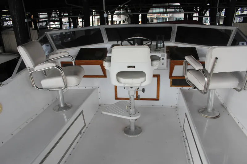 Slide: The Image of 1974 Hatteras 58 Yachtfish helm with three white captain chairs and steering wheel. - 38