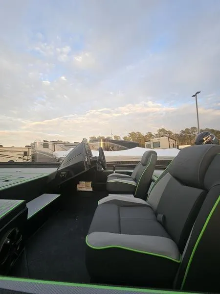 Slide: The Image of 2025 Xpress H20C Crappie boat interior with gray and green seating under a cloudy sky. - 6