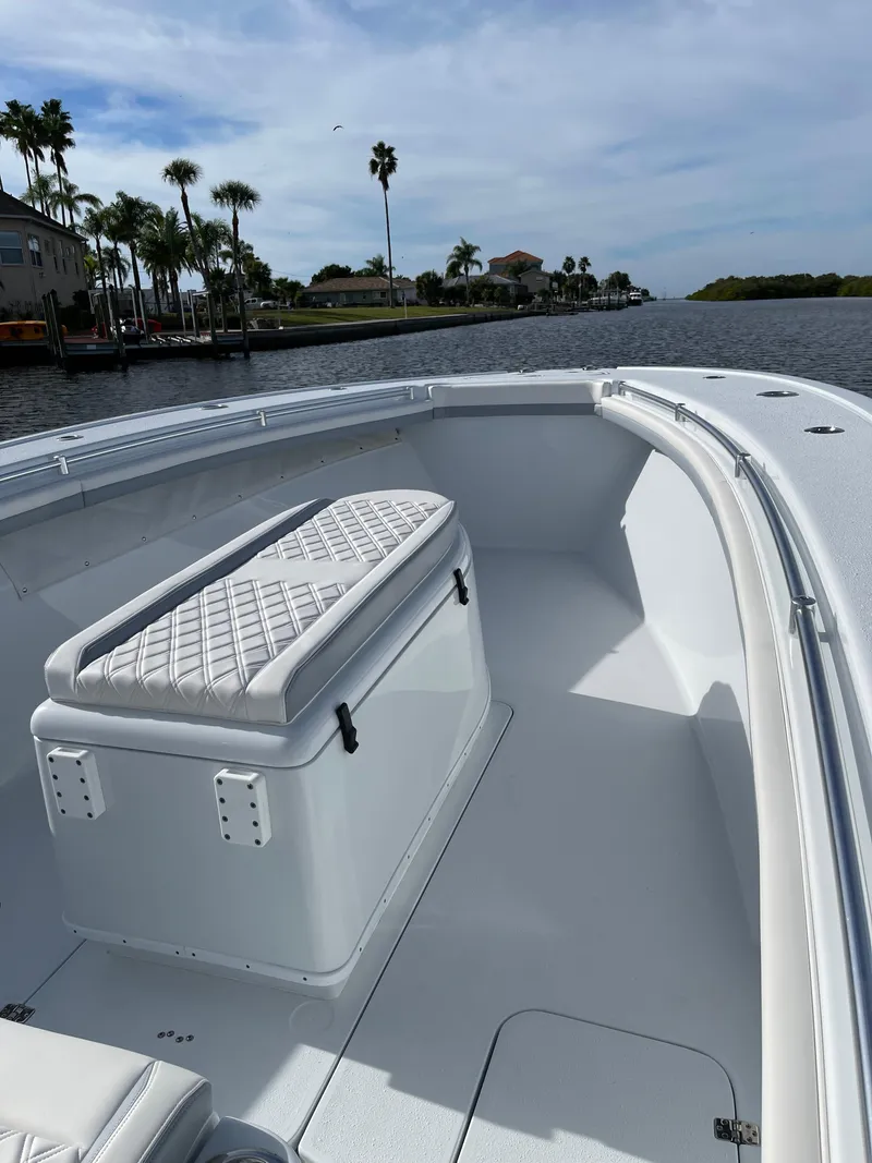 Slide: The Image of 2022 Yellowfin 34 boat with cushioned seating, cruising on a scenic waterway. - 17