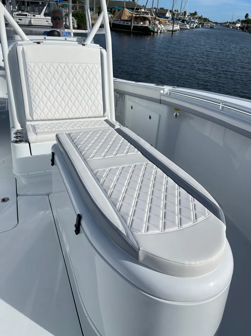 Slide: The Image of 2022 Yellowfin 34 boat with white cushioned seating, docked by a marina. - 45
