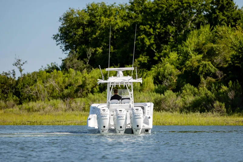 Slide: The Image of 2022 Yellowfin 34 boat with triple engines cruising on a serene lake. - 6
