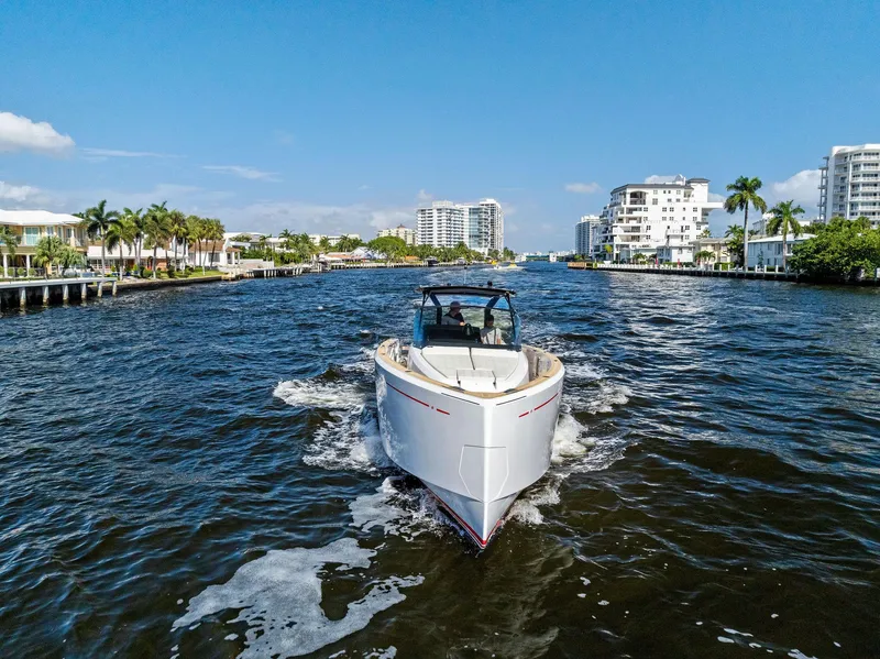 Slide: The Image of Pardo Yachts 38 cruising through a scenic waterway, surrounded by modern buildings and palm trees. - 16