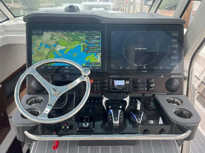 Slide: The Image of 2023 Pursuit 428 Sport boat dashboard with navigation screens and steering wheel. - 15