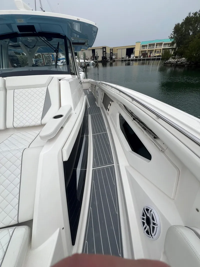 Slide: The Image of 2023 Pursuit 428 Sport boat docked, featuring sleek white design and spacious deck. - 21