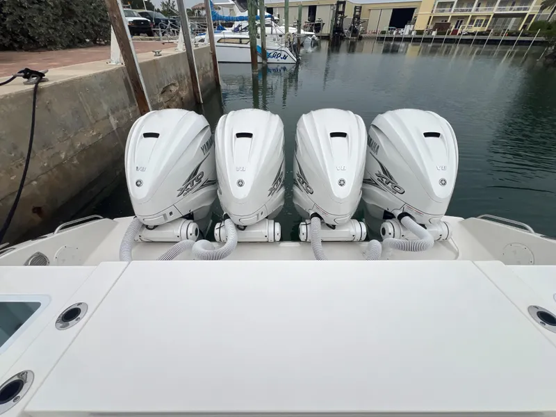 Slide: The Image of 2023 Pursuit 428 Sport boat with four powerful outboard engines docked at marina. - 23