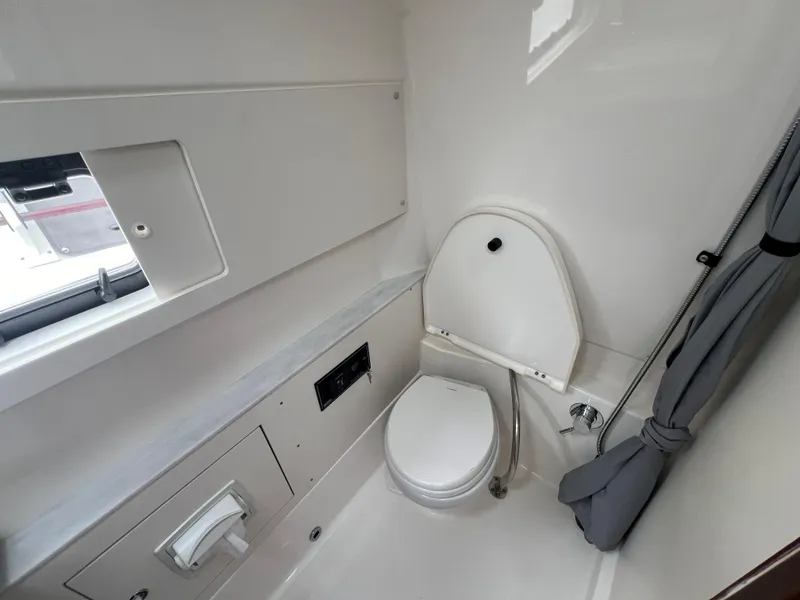Slide: The Image of 2023 Pursuit 428 Sport boat bathroom interior with toilet and window. - 32
