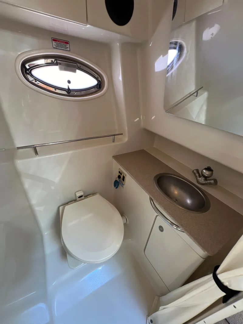 Slide: The Image of 2006 Sea Ray 290 Sundancer bathroom with sink, toilet, and porthole window. - 14