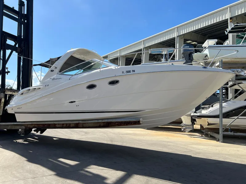 Slide: The Image of 2006 Sea Ray 290 Sundancer boat on lift, white exterior, sunny day. - 2