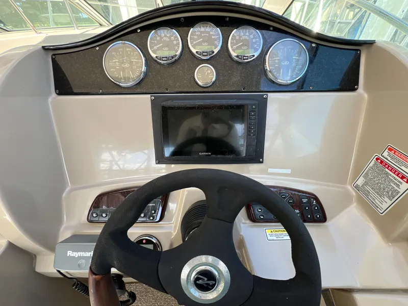 Slide: The Image of 2006 Sea Ray 290 Sundancer helm with gauges, steering wheel, and navigation display. - 27