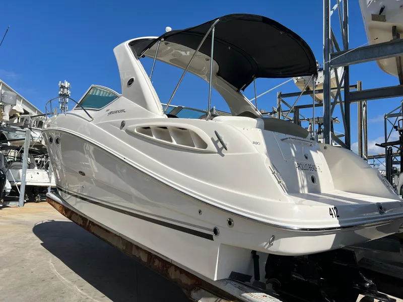 Slide: The Image of 2006 Sea Ray 290 Sundancer boat with black canopy, docked under clear blue sky. - 3