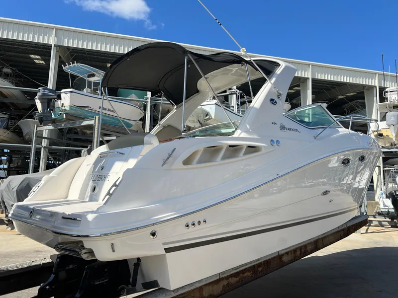 Slide: The Image of 2006 Sea Ray 290 Sundancer boat in storage, featuring sleek white design and covered cockpit. - 37