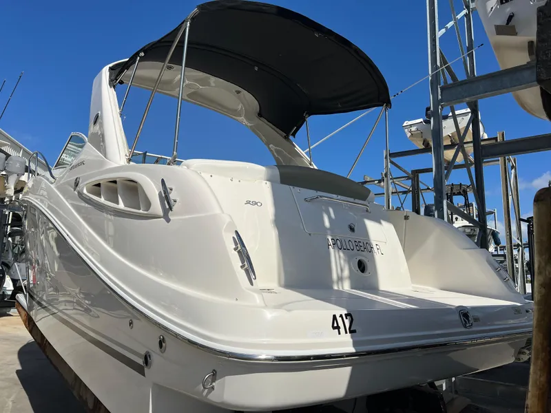 Slide: The Image of 2006 Sea Ray 290 Sundancer boat with canopy, docked under clear blue sky. - 38