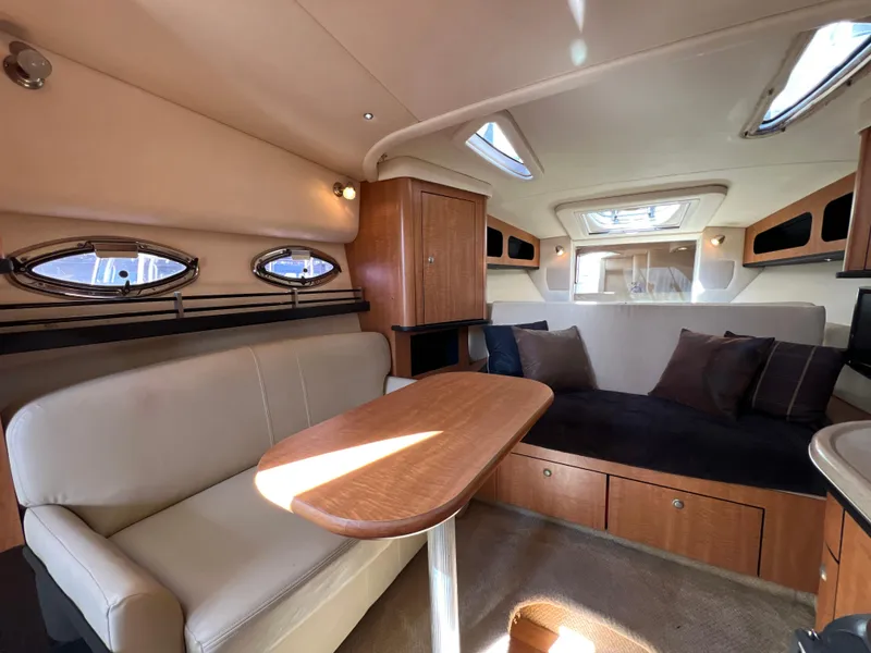 Slide: The Image of Interior of 2006 Sea Ray 290 Sundancer with cozy seating and wooden table. - 8