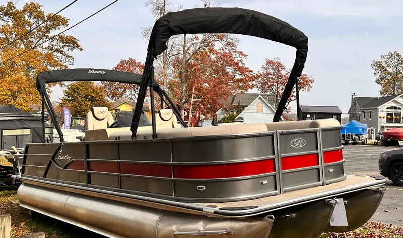 Slide: The Image of 2025 Bentley Pontoons Legacy 243 Swingback with canopy, parked outdoors in autumn setting. - 9