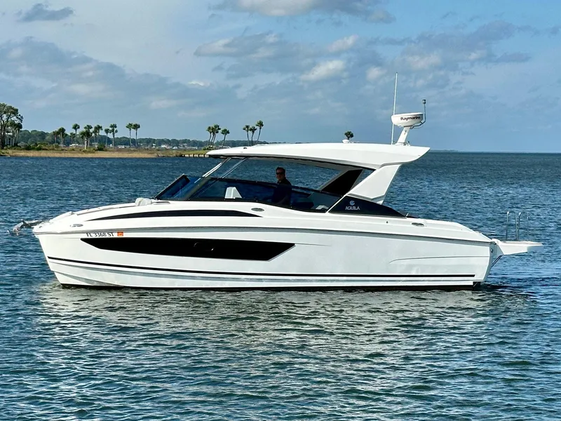 Slide: The Image of 2020 Aquila 32 Sport boat cruising on a calm sea under a partly cloudy sky. - 2