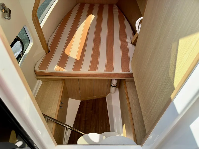 Slide: The Image of Interior cabin of 2020 Aquila 32 Sport with striped bedding and wooden finish. - 26