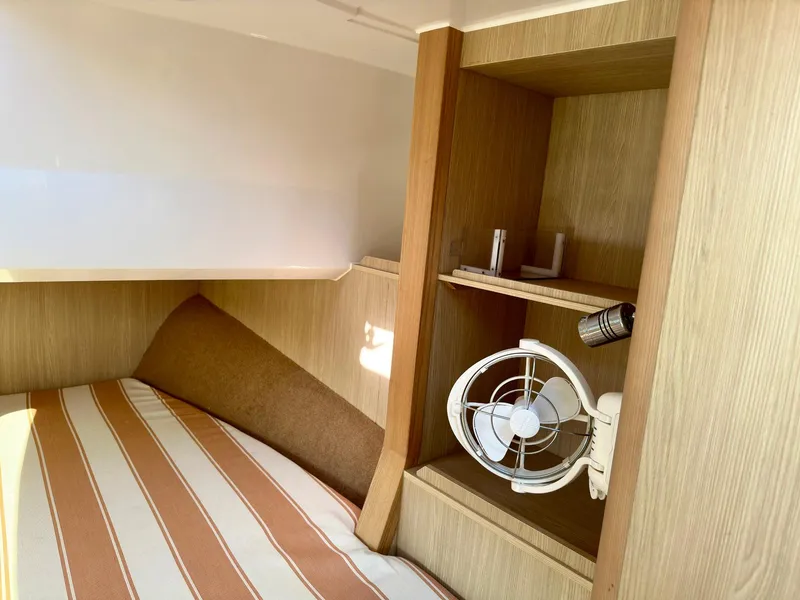 Slide: The Image of Cozy cabin interior of 2020 Aquila 32 Sport with striped bedding and wooden shelves. - 28
