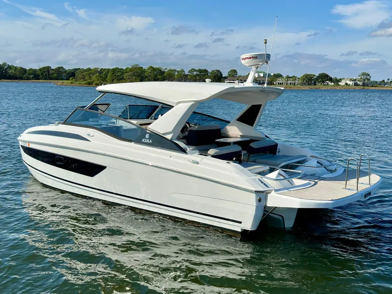 Slide: The Image of Aquila 32 Sport 2020 boat cruising on a serene lake under a clear blue sky. - 3