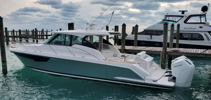 Slide: The Image of 2022 Tiara Yachts 43 LE docked in marina, overcast sky, calm water. - 2